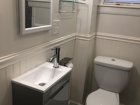 Newly tiled bathroom with updated fixtures such as toilet and sink.