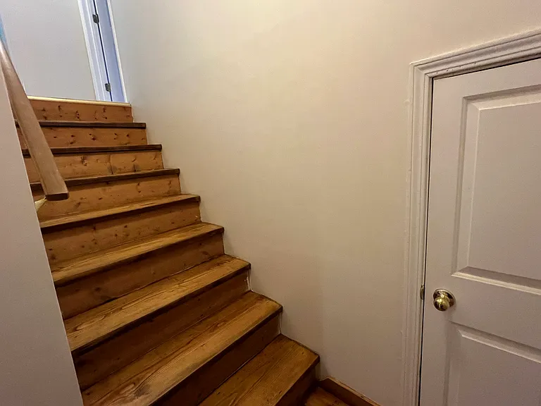 Stairs leading to upstairs bedrooms. Small door on landing has breaker box and small storage.