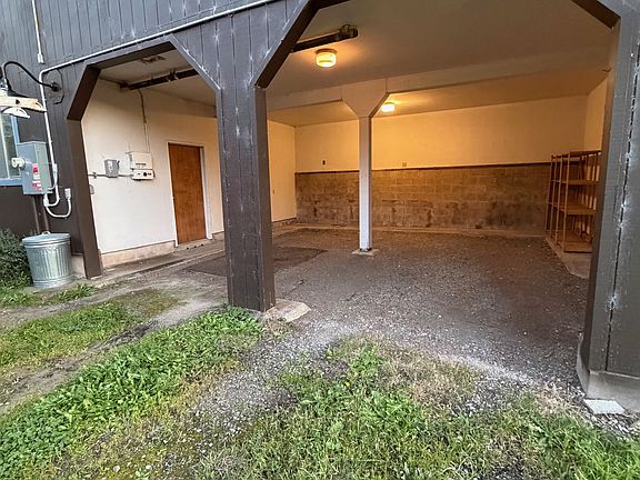 Garage space two vehicles, high overhead for truck or van, gravel floor.