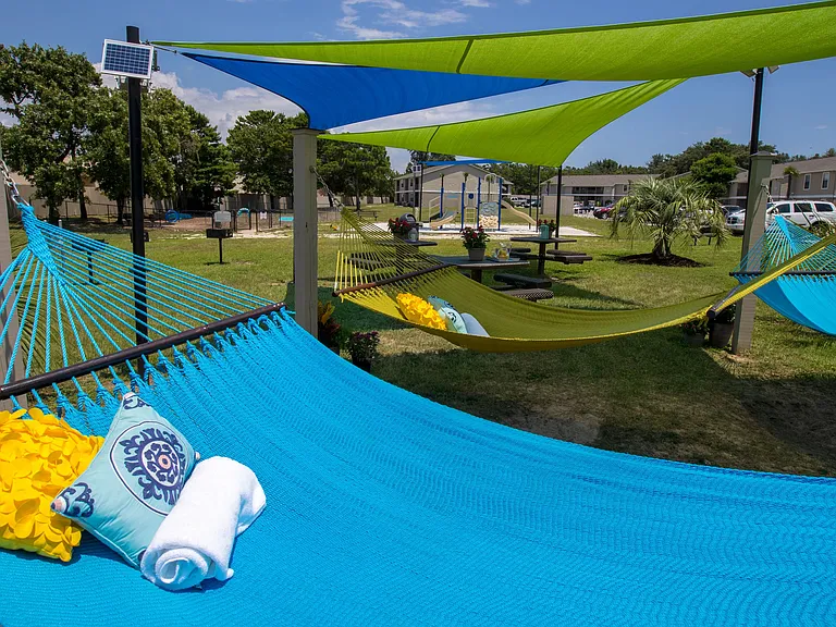 Unwind in our serene leisure area equipped with hammocks and picnic tables under colorful sail shades for an enjoyable outdoor experience.