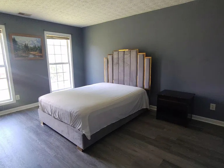 Spacious bedroom featuring two large windows for natural light, durable flooring, and room for a full furniture setup.