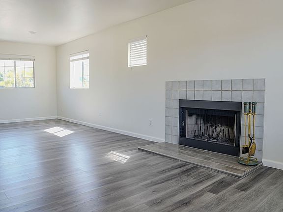 Living room view of the fireplace and area for a dining table. The kitchen is to the left of the middle window.