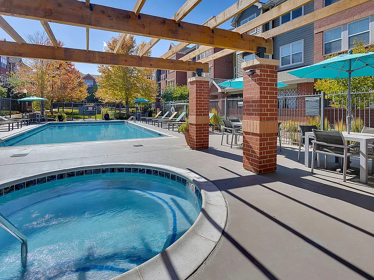 Inviting outdoor space featuring a sparkling pool and relaxing hot tub, surrounded by stylish seating and modern patio umbrellas.