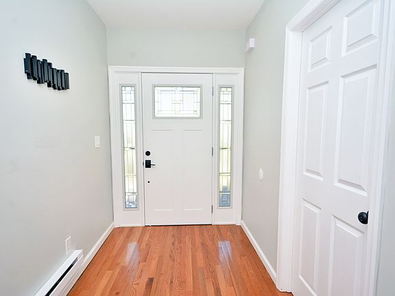 Wide foyer with wall mounted metal coat rack that looks like wall decor.