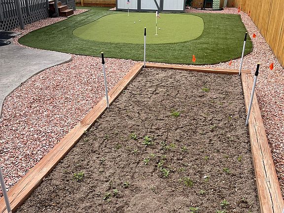 Raised garden that is on automatic sprinkler system, astroturf 2-hole putting green and shed.