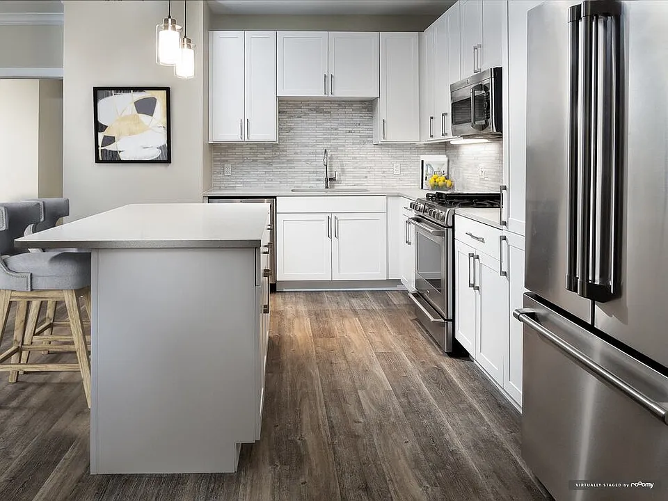 Signature Collection kitchen with white cabinetry, light grey quartz countertops, white marbled subway tile backsplash, stainless steel appliances, and hard surface flooring