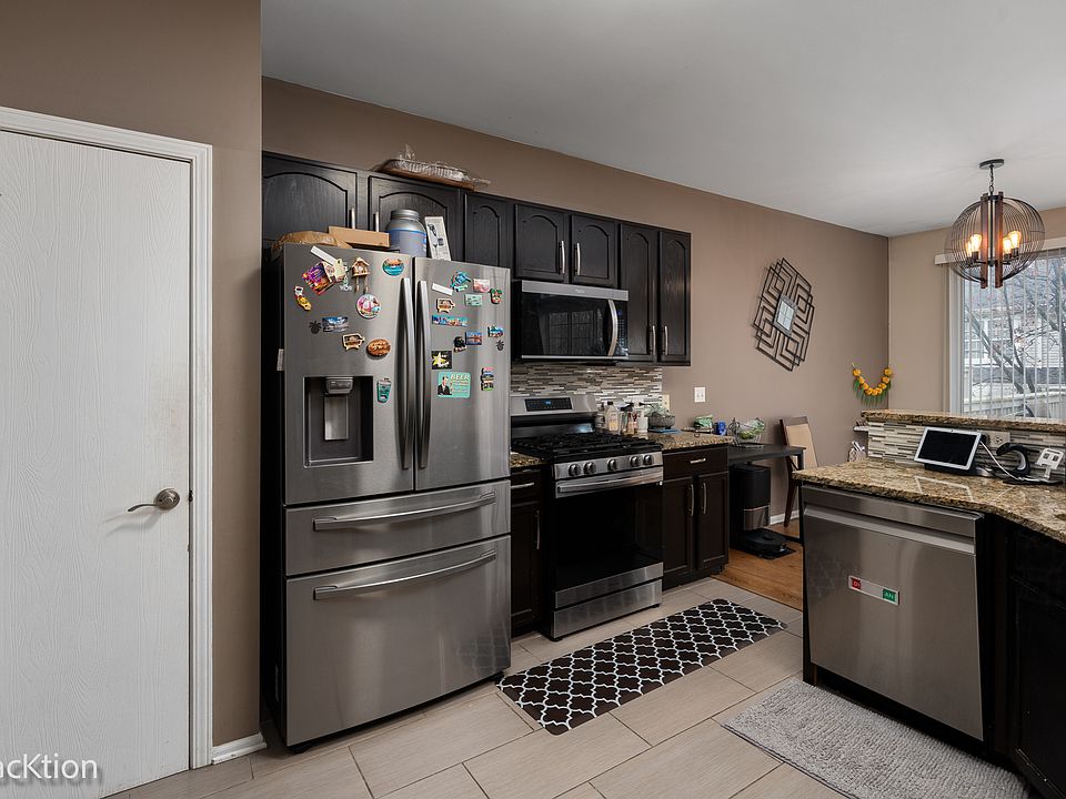 Kitchen with stainless steel appliances, dark cabinets, and granite countertops.