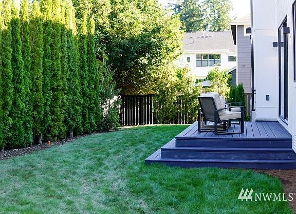Fully fenced yard with a privacy hedge.>