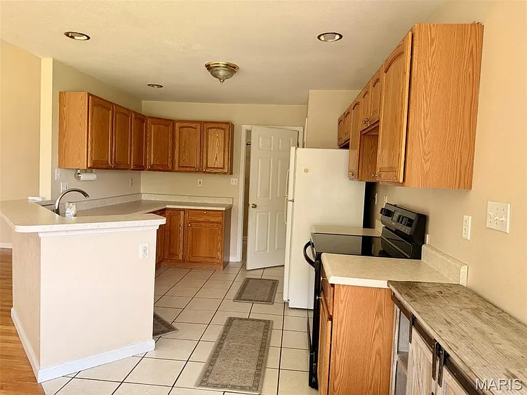 Kitchen featuring wood cabinets, white countertops, tile flooring, and recessed lighting