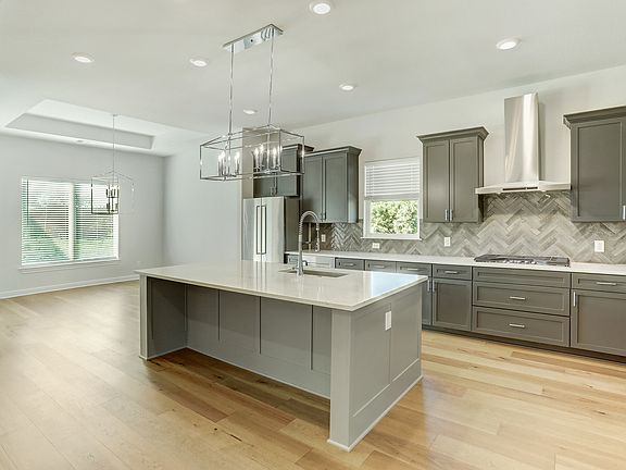 The kitchen has dark grey cabinetry, quartz countertops and stainless steel appliances.