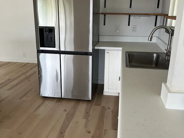 Open concept kitchen. Open shelving. Stainless steel refrigerator with ice maker and water dispenser.
