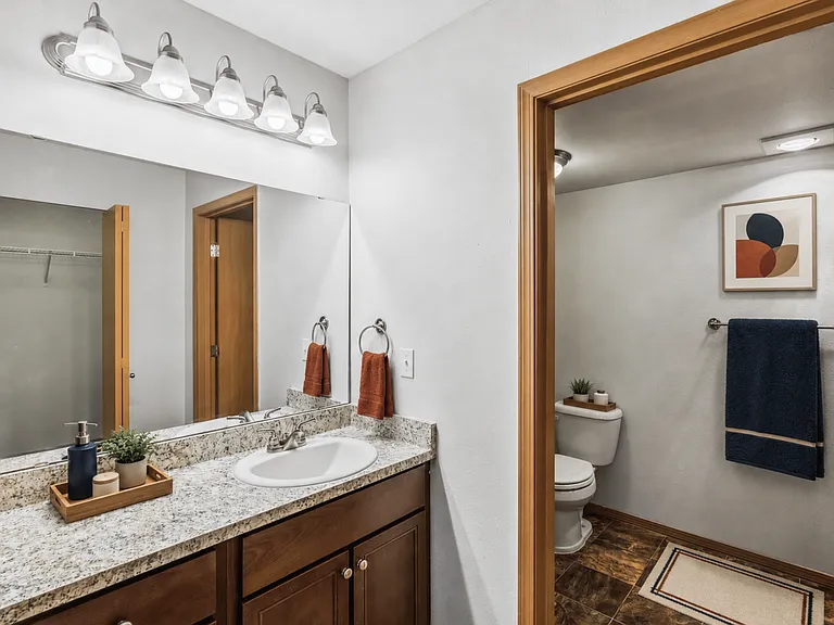 A bright bathroom with generous counter space and a private toilet area.