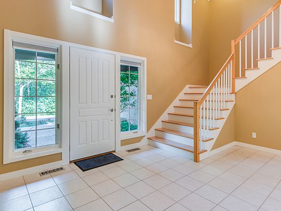 Living room with 22' high ceilings, wood floors, fireplace, and two sliding doors with transom windows above, opens to the wraparound deck.