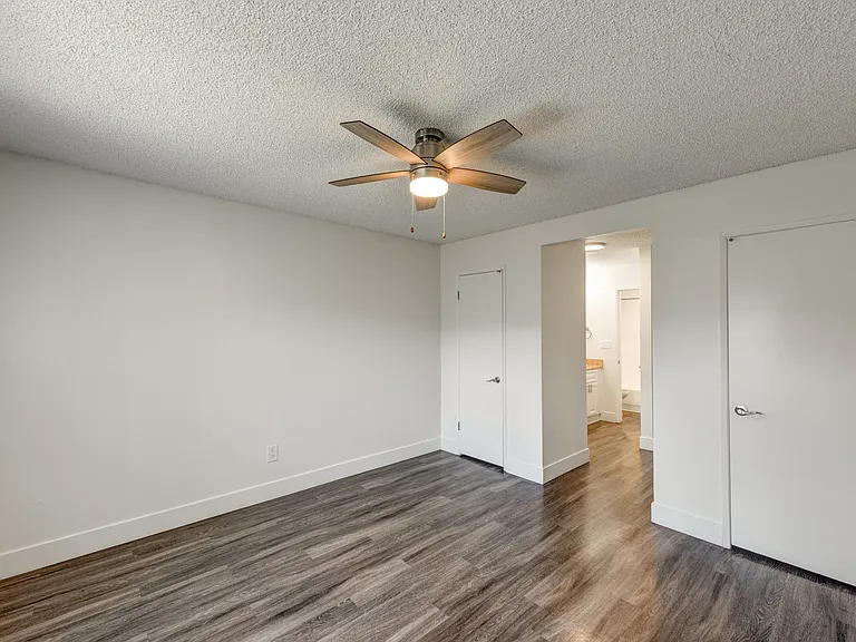 an empty bedroom with a ceiling fan and wood flooring