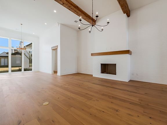 Living room with exposed beams, hardwood floors, and a modern brick fireplace