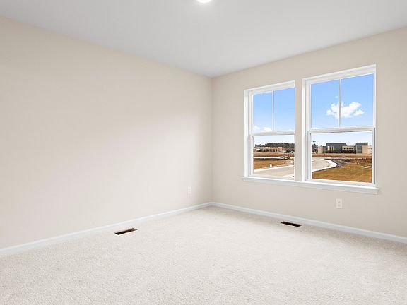 Carpeted owner s suite with large double window in a DRB Homes Glenshaw plan at The Village of Colle