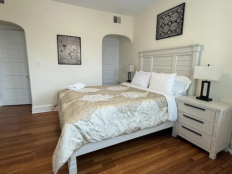 Furnished bedroom with hardwood floors, a full bed, matching nightstands, and dual lamps for convenient bedside lighting.