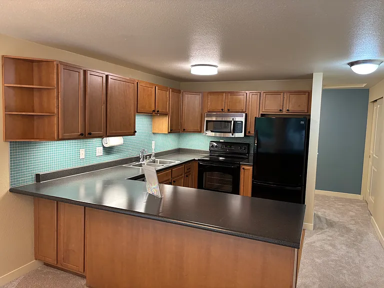 Kitchen with maple cabinets, bar seating, dishwasher and microwave.
