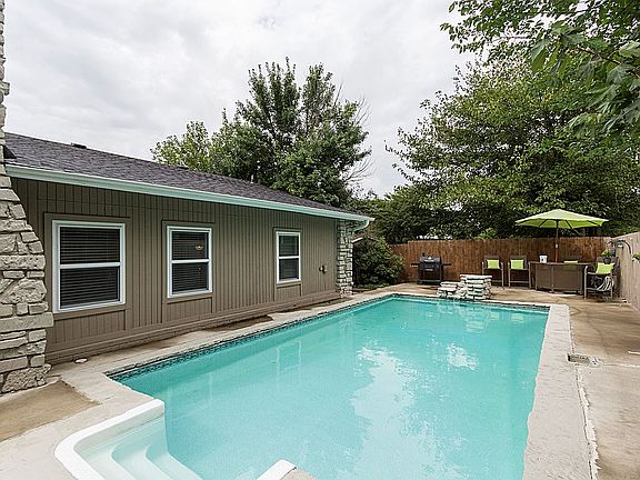 Sparkling in-ground pool showcases a natural water feature created by limestone coordinating with stone accents on the house.