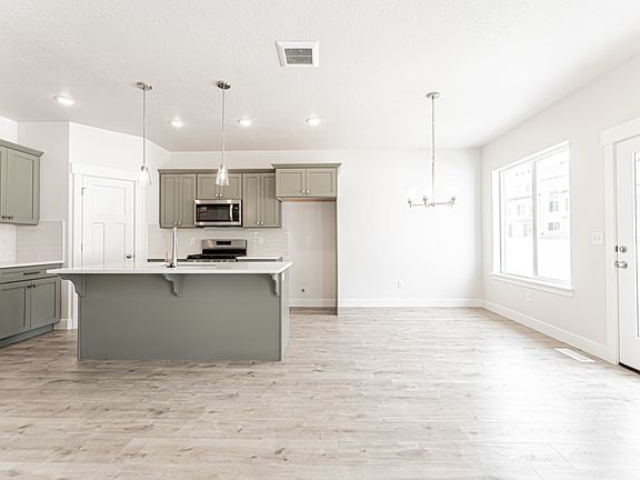 Kitchen featuring gray cabinetry, appliances with stainless steel finishes, an island with sink, a textured ceiling, and recessed lighting