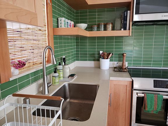 Large inset stainless steel sink. Light colored granite countertops. Beautiful Heath ceramic tiles. Floating shelves to showcase your pretty kitchen wares.