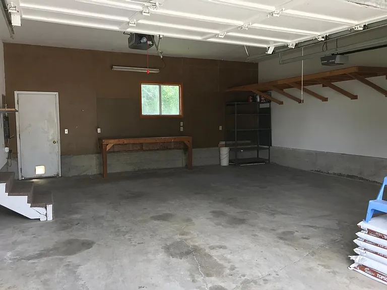 2 car garage; tool bench; metal shelf; up-rise storage. White door leads to back yard. Steps on left of picture lead to dining room