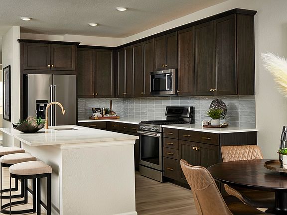 A modern and well-equipped kitchen with dark wood cabinets, stainless steel appliances, and a white