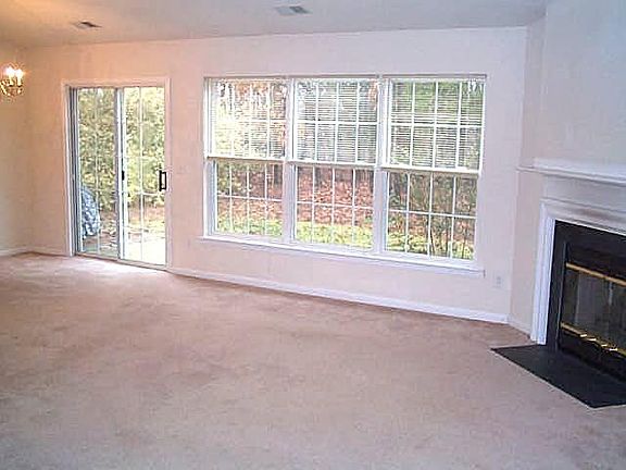 great room with gas log fireplace with a wall of windows looking towards the rear yard.