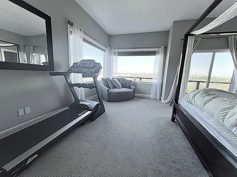 Primary bedroom 2 with treadmill and revolving sofa seat chair to enjoy the views.