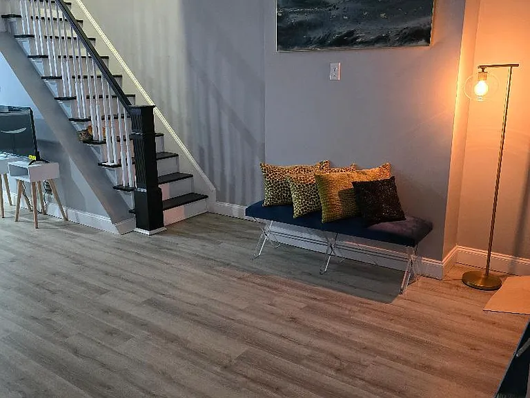 Open common area with durable wood-look flooring, staircase access, and a seating nook ideal for relaxing or waiting.
