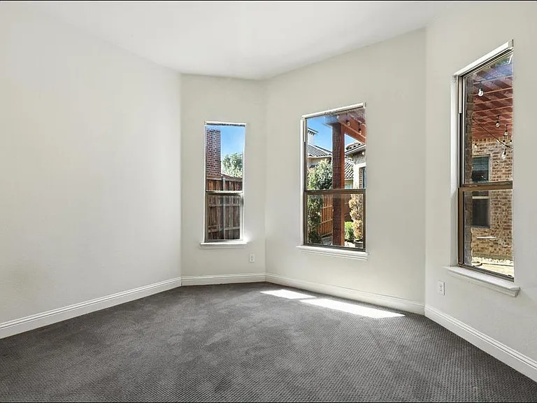 Room with three windows, white walls, and dark gray carpeting