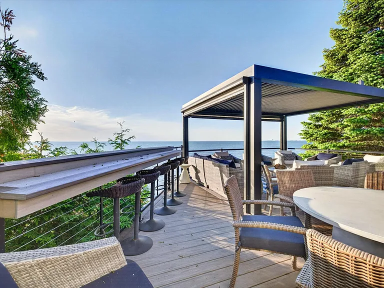 Round table with seating for 8 next to the pergola and bar.