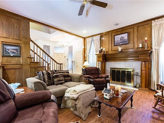 The living room with a custom built fireplace with a handmade wood mantel, marble surround, and gas logs.  Ceiling fan.  Luxury woodlike vinyl flooring.