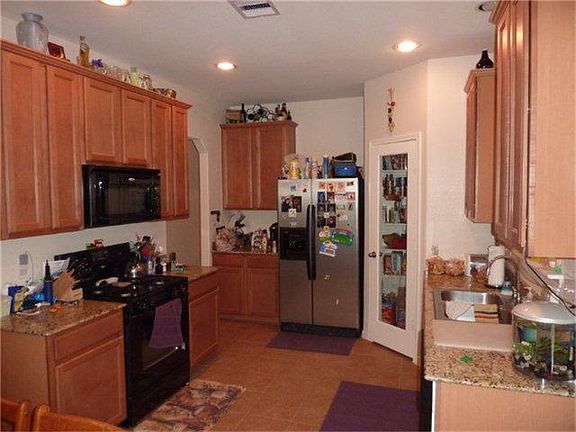 Central kitchen has granite counters and tiled back splash