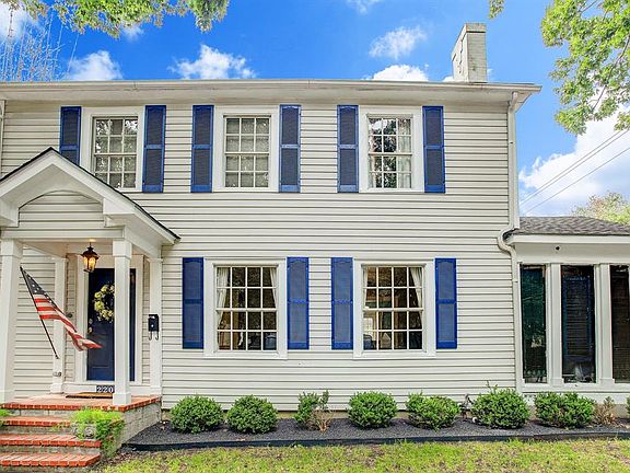 Blue shutters frame large windows that provide ample natural light to the home