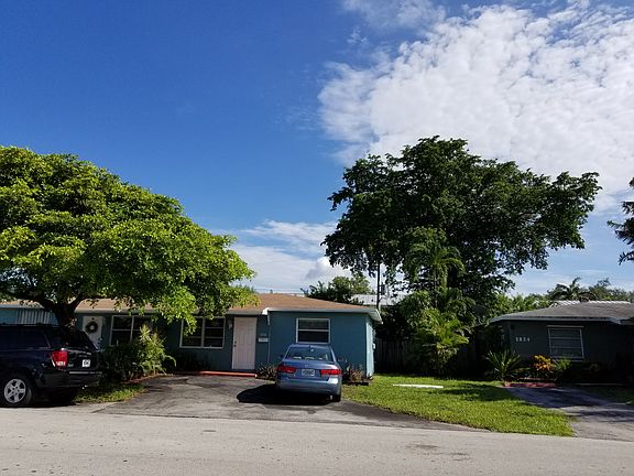 Front shows Driveway and additional parking under tree
