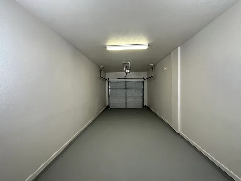 Spacious and well-lit garage with modern automatic door, perfect for secure parking and storage. Spacious and well-lit garage with modern automatic door, perfect for secure parking and storage.