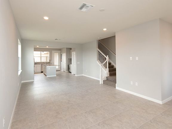View of gathering room into kitchen with stairs leading to the bedrooms on the 2nd floor