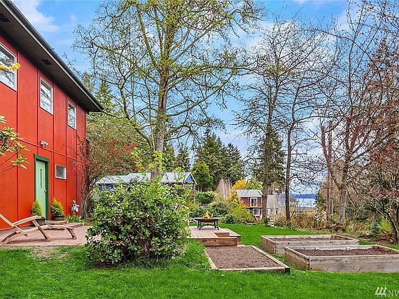 East side yard showing sweet brick patio, raised beds and the peek-a-boo view of Puget Sound and Seattle. Door on left leads into garage.