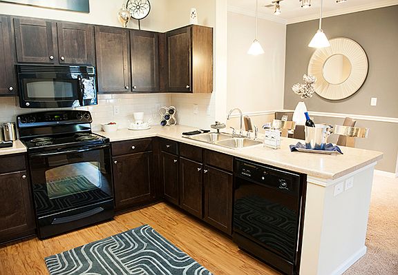 Dark wood cabinets, black appliances, and vinyl flooring in