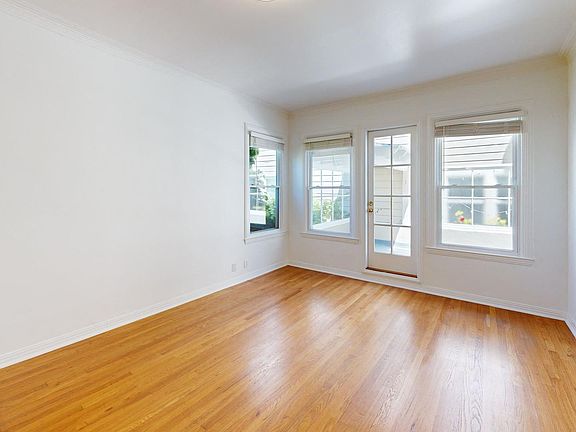 Sunlit room with a large window and a wood-like flooring