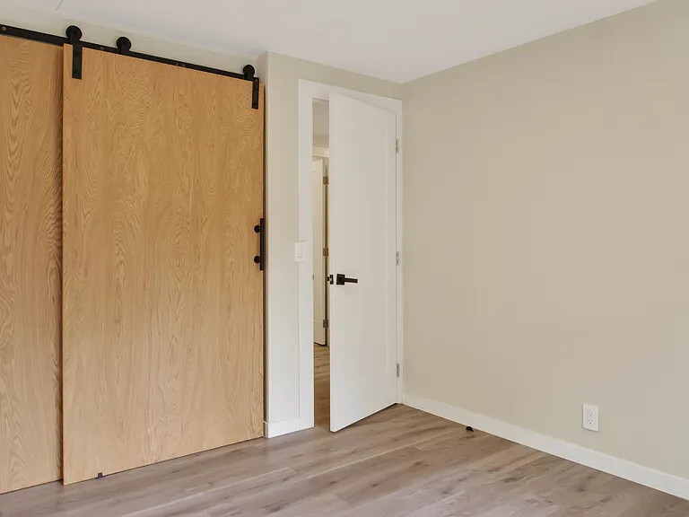 Third Bedroom with Sliding Barn Door Closet and Hardwood-Style Flooring