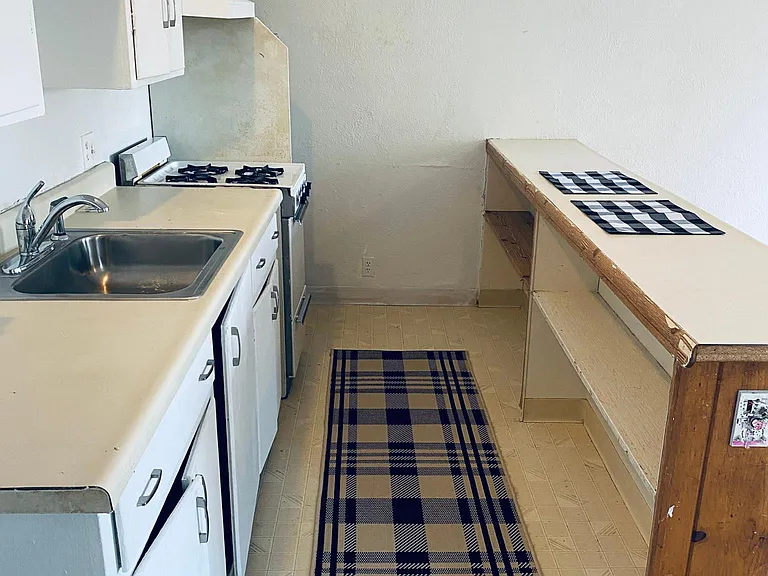 Kitchen has a stove, refrigerator and sink.