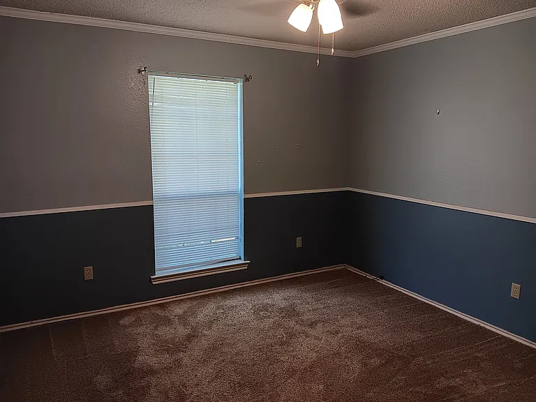 Two tone blue bedroom with ceiling fan, crown moulding, plush carpet & wall closet with light. Large enough for complete bedroom set.