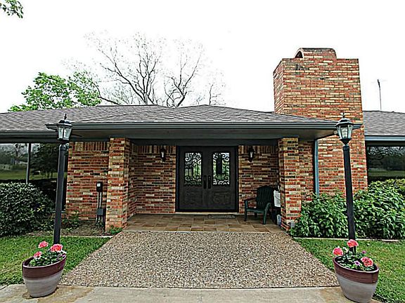 THE GORGEOUS CUSTOM IRON FRONT DOOR AND COVERED PORCH INVITES YOUR GUESTS INSIDE THIS LOVELY RANCH S