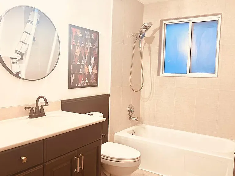 Gorgeous and Warm bath with new tile, new fixtures, new flooring. Beautiful black fixtures offset the ivory walls, Benjamin Moore Chocolate wainscotting, and Beige Shower Tile.