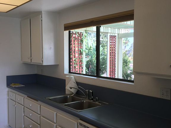 Kitchen with window looking out to tree top view and grass