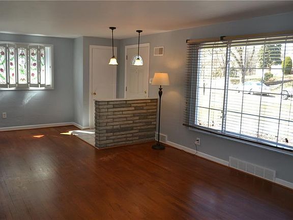 Combo living room and dining room with lots of natural light, stone divider, pendant lighting and original hardwood flooring.