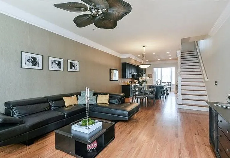 Open-concept living space featuring wood-finish flooring, a contemporary ceiling fan, and crown molding