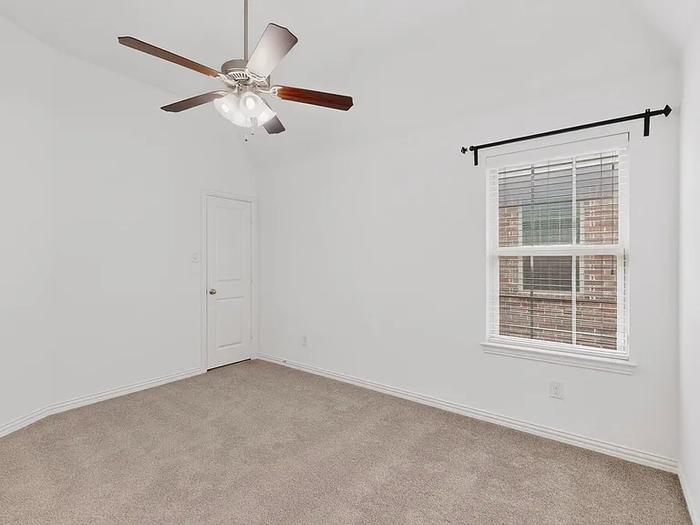 A bright bedroom featuring a ceiling fan, a window, and a walk-in closet